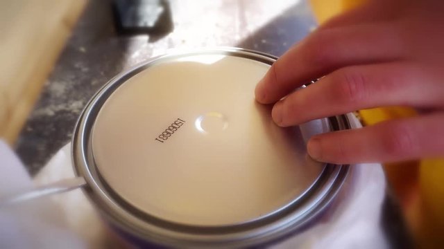 a young man opens a jar of lacquer on wood.
