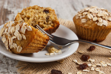 Fresh muffins with oatmeal baked with wholemeal flour on white plate, delicious healthy dessert