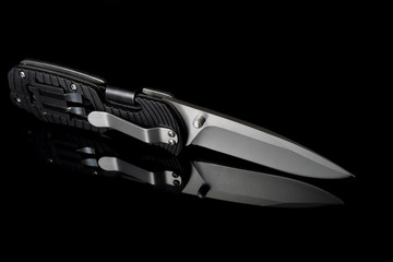 folding knife with dark background and reflection.