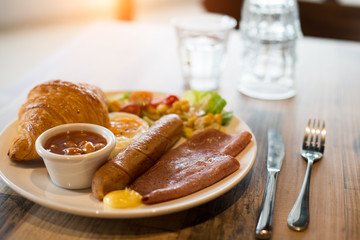 English breakfast with fried eggs, bacon, sausages, beans, toasts and fresh salad
