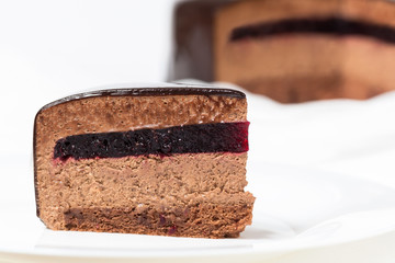 Slice of chocolate mousse cake with blackberry jelly and mirror glaze