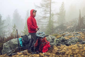 Hiker travels in the mountain forest in the mist with a backpack. Concept of travel and Hiking in...