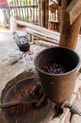 Fototapeta na wymiar old vintage manual coffee mill or grinder with coffee been and old vintage kettle in background with the scene of the shade of the housing of the hill tribes, soft focus, selective focus.