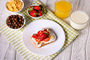 breakfast: Fresh toast with strawberry, banana and nuts, cornflakes, orange juice, milk