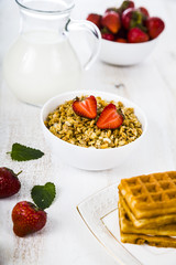 Granola with strawberry on a wooden table.