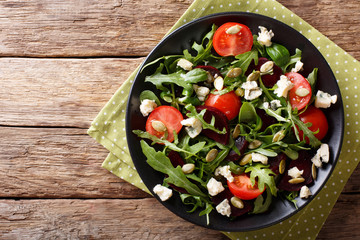 fresh salad with beets, arugula, tomatoes, blue cheese and pumpkin seeds close-up on the table. horizontal top view