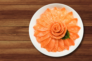 Top view of salmon sashimi serve on flower shape in white ice bowl boat on wood table background,...
