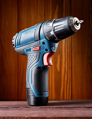 Cordless drill or screwdriver isolated on wooden background