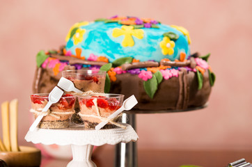 Delicious mousse covered in strawberry topping, presented inside small glasses with spoons attached, colorful cake background, pastry concept