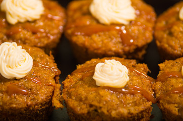 Delicious brown colored muffins lined up with caramel and cream topping, as seen from above angle, pastry concept