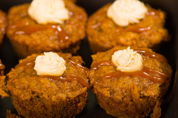 Delicious brown colored muffins lined up with caramel and cream topping, as seen from above angle, pastry concept