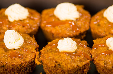Delicious brown colored muffins lined up with caramel and cream topping, as seen from above angle, pastry concept
