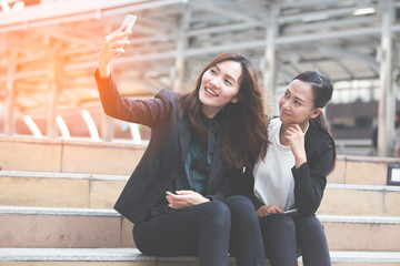 Young businesswomen taking a selfie in the place while sitting with friend.