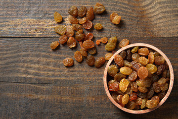 Raisins in a wooden bowl on a wooden background