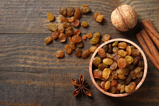 Raisins in a wooden bowl on a wooden background