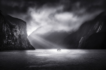 A Tour Boat makes it way through Milford Sound hi lighted by sun rays.