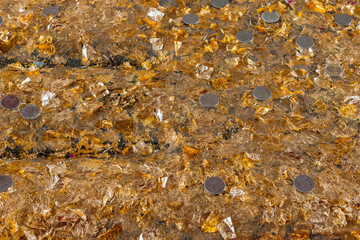 Close up of gold leaf flakes and coins in temple, thailand