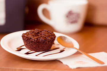 Delicious chocolate cake in plate on rustic wooden table with a spoon in plate