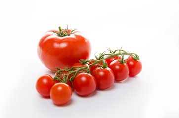 Small cherry tomatoes with green leaves on a white background. Isolated
