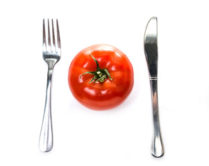 Fork and knife on the sides of a tomato. Isolated