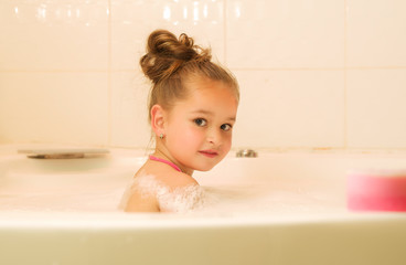 little beautiful girl playing with water and foam in bath