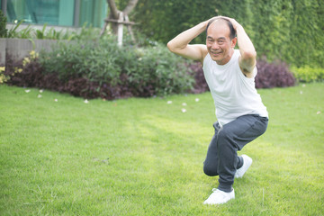 Asian old man scotch Jum on mat in field, outdoor exercise concept.