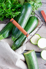 Fresh green zucchini in a metal basket on a wooden table, top view, selective focus