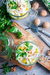 Salad with chicken in a glass jar with walnuts, top view, selective focus
