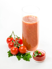 Composition from a tomato and a glass of juice on a white background.