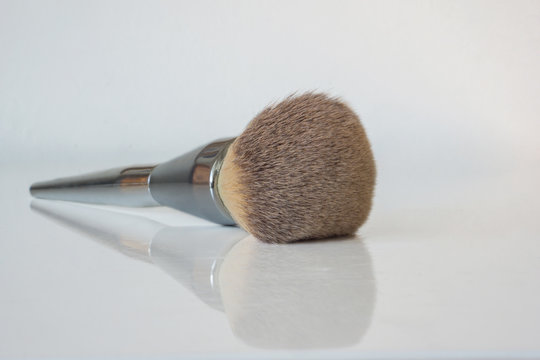 Close-up of a professional powder brush with a reflection on a white table.