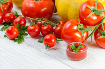Composition of large tomatoes, cherry, pumpkin, and a glass of juice on a paternal background.