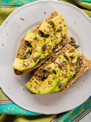 Avocado cereal sandwich for healthy snack with seeds on green napkin