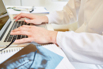 Obraz na płótnie Canvas Arzt tippt auf Tastatur von Laptop