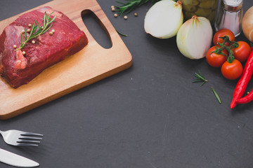 Raw beef on a cutting board  with spices and ingredients for cooking.