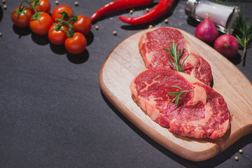 Raw beef on a cutting board  with spices and ingredients for cooking.