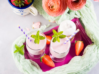 Strawberry milk shake in glasses for romantic summer healthy breakfast. Summer table setting with ranunculus flowers