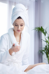 young woman in bathrobe sitting on bed at home