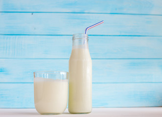 
Milk in a glass bottle on a blue wooden background. Dietary breakfast.