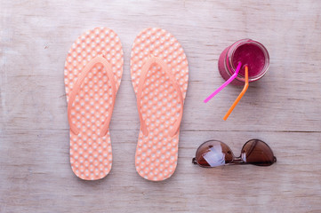 Flip flops, sunglasses and smoothie on wooden background