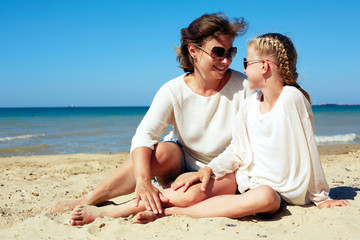 Fototapeta premium Portrait of a happy parent and child resting on the beach