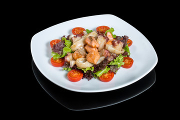 Seafood salad with octopus, shrimps, squid and vegetable on a withe plate. On a black background with reflection