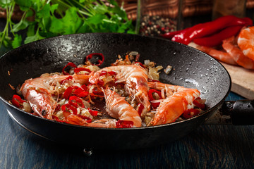 Shrimps roasted on frying pan with onion, garlic and chili