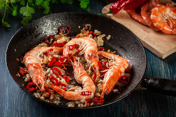 Shrimps roasted on frying pan with onion, garlic and chili