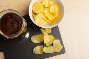 Lager beer in glass and potato chips on wooden background