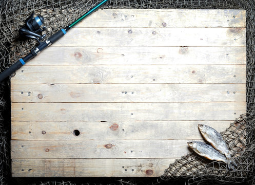 Fishing tackle and dried fish still-life on the wooden background.