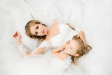 Obraz na płótnie Canvas The bride with daughter lie on the bed