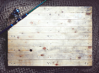Top view of fishing nets and spinning rod on the wooden background.