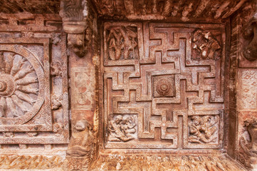 Background of Indian rock-cut architecture. Ceiling with carved maze with sun symbols. 6th century cave temple in town Badami, India
