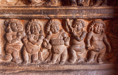 Example of Indian art carvings with singing and dancing party of ancient people on wall of 6th century temples in Badami, India
