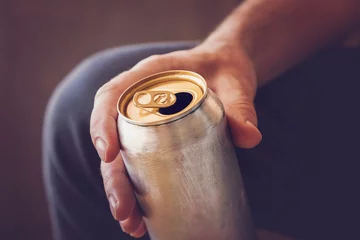 Foto op Canvas Man drinking a cold beer after work in the evening. Hand holding a aluminum can. © fotoduets